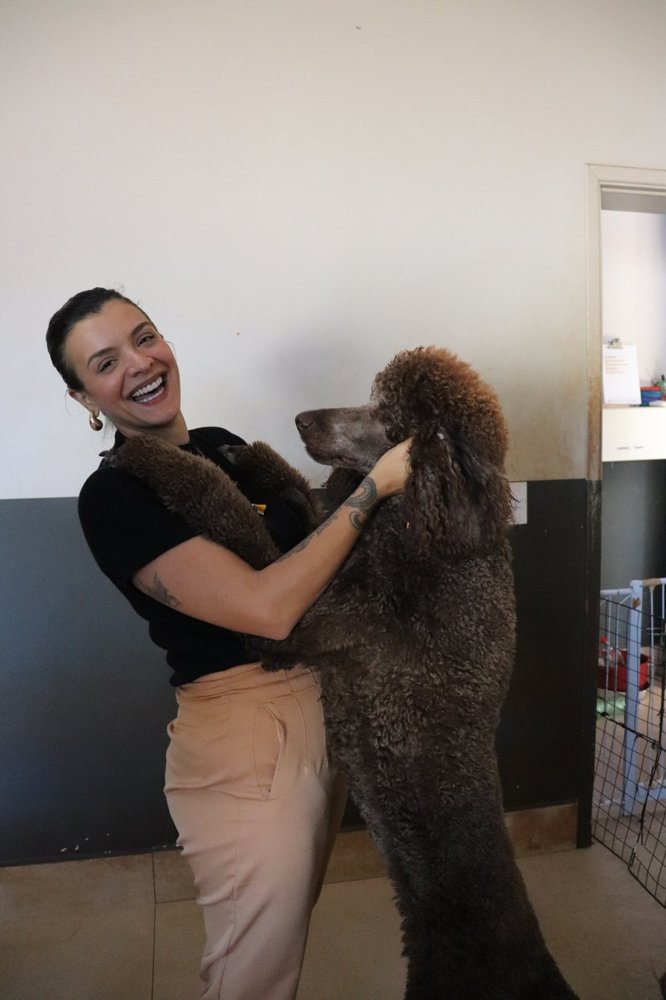 Tia Carol da Casa da Flor com um poodle no colo
